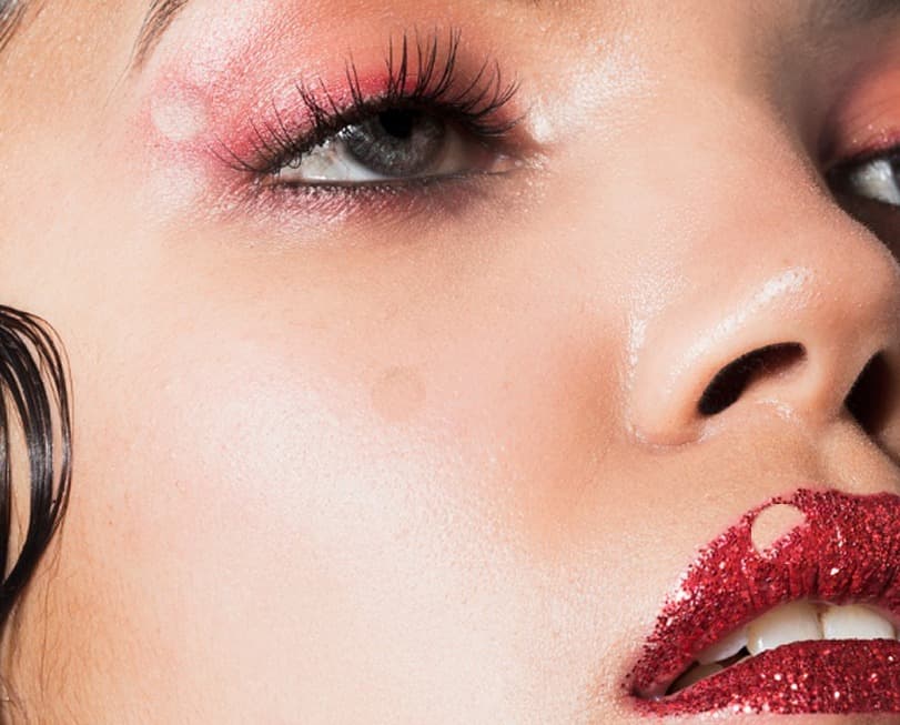 Close-up of a face with red glitter lips and pink eyeshadow